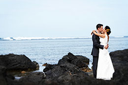 Bride and Groom kiss on the black rocks of Princeville, Hawaii