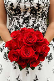 Red roses in front of a black and white wedding dress