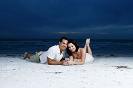 Engaged couple lays on Clearwater Beach at dusk