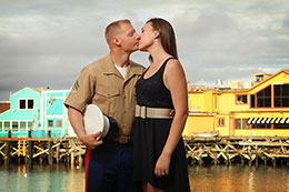 Engaged military couple kiss on Monterey Warf