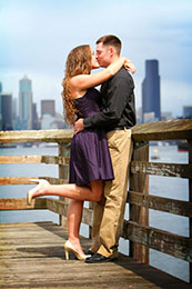 Engaged couple kiss with Seattle skyline in background