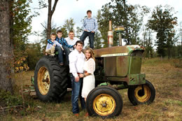 The Duke family poses on an old John Deere tractor