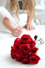 Bride signs mariage license with roses in foreground