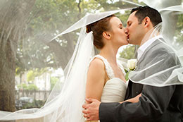 Bride and Groom kiss beneath long flowing veil