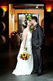 Bride and Groom sneak a kiss in the barrel room of JM Cellars