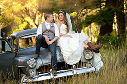 Wedding couple sits on an old junkyard car