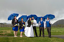 Wedding party with blue umbrellas in the rain