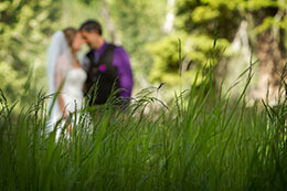 Wedding couple kissing behind the foreground of grass