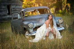 Beautiful Bride sits on an old junkyard car