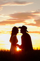 Radient sunset silhouettes bride and cowboy groom