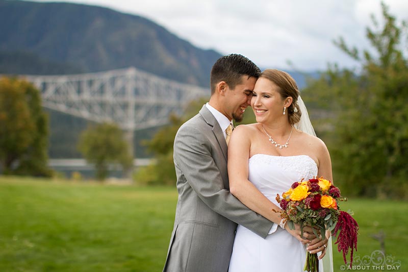 Bride and Groom cuddle with Bridge of the Gods in background on Thunder Island