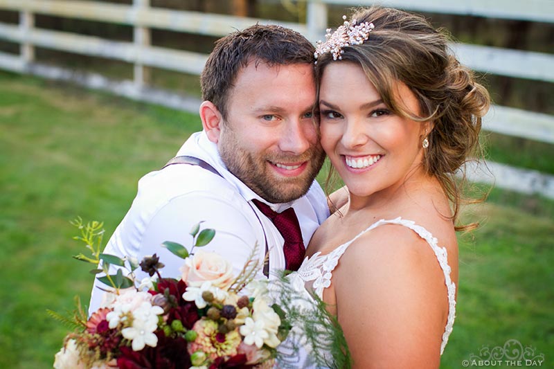 Bride and Groom pose with a white fence