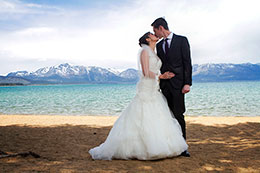 Bride and groom kiss on the beach of Lake Tahoe