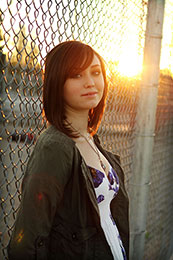 Cassidy leans on a schoolyard fence at sunset