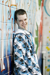 Mark poses for senior photos with grafiti wall