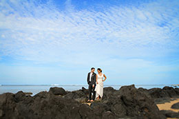 Bride and groom stand on black rocks of Kawaii