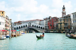 A gondola crosses the Grand Canal in front of Rialto Bridge in Venice, Italy