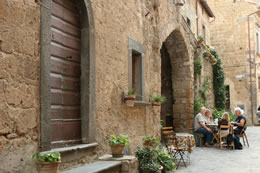 People eat and relax along a back street in Civita, Italy