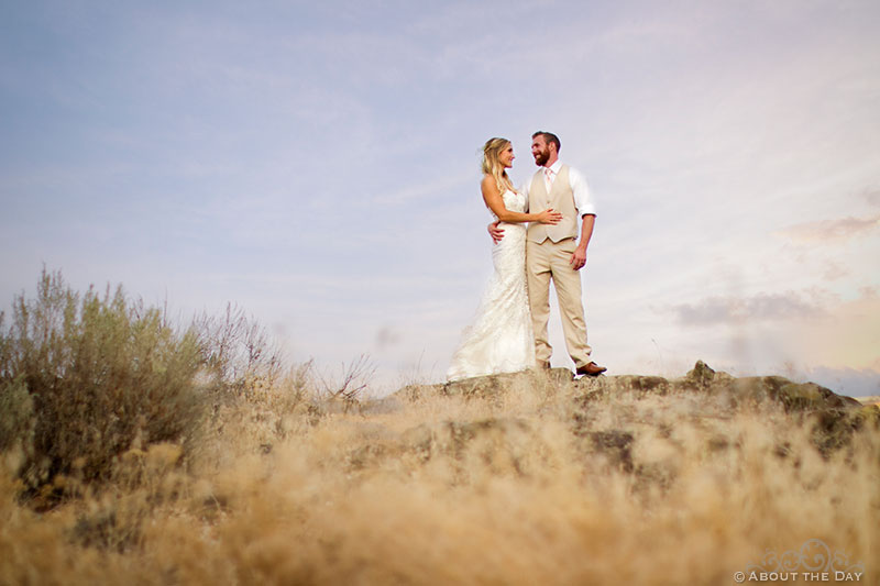 Bride and Groom stand on black rocks during sunset at Shadow Lake Ranch