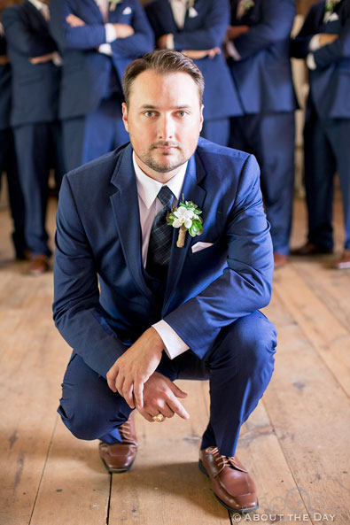 Groom poses in front of his groomsmen in the barn at Youngs Dairy Farm in Auburndale, WI