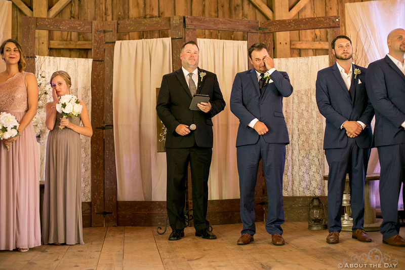 Groom cries as Bride walks down the isle in the barn at Youngs Dairy Farm in Auburndale, WI