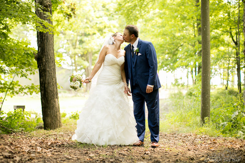 Bride and Groom kissing in the woods at Youngs Dairy Farm