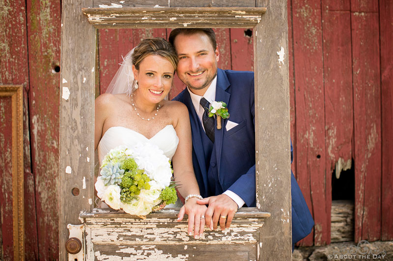 Bride and Groom looking though old wooden door at Youngs Dairy Farm