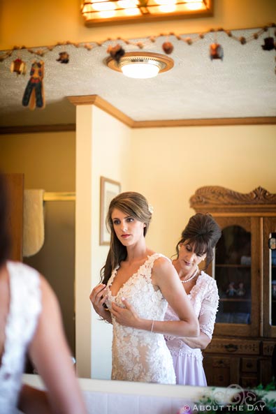 Beatuiful Bride is helped by her mother in mirror