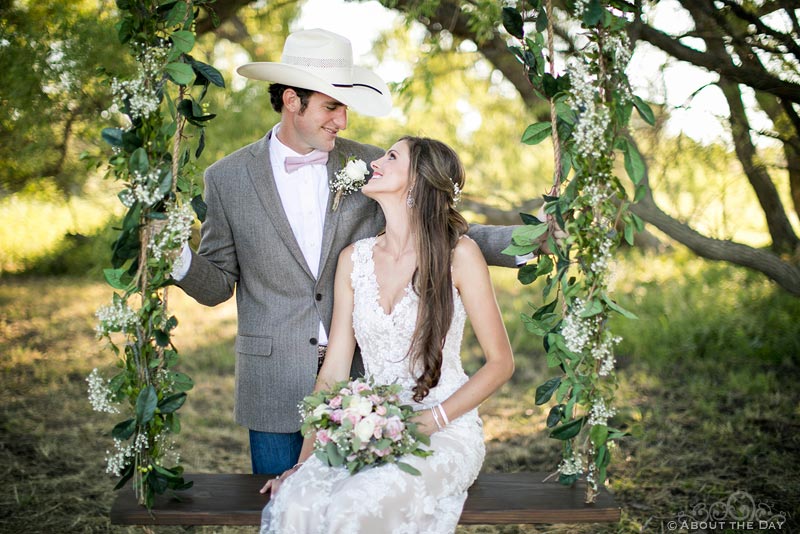 Bride and Groom pose in a swing at the wedding ceremony site