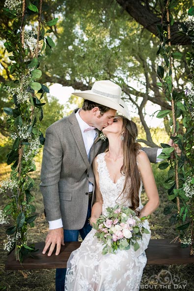 Bride and Groom kiss in a swing at the wedding ceremony site