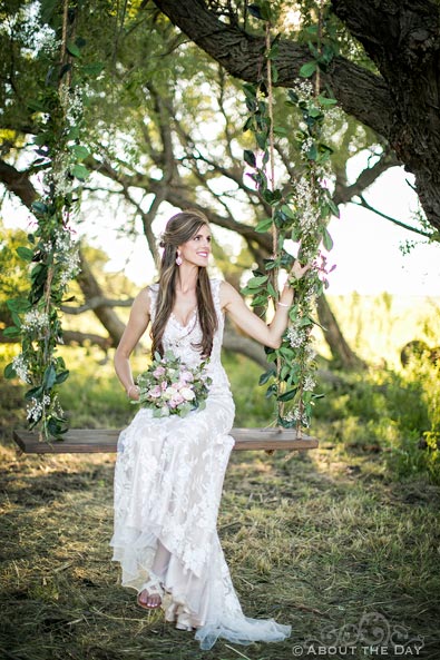 Beautiful Bride sits in a rope swing with flowers at Haythorn Land & Cattle Co