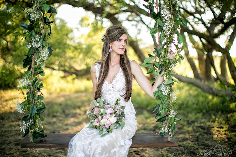 Stunningly beautiful Bride sits in a rope swing with flowers at Haythorn Land & Cattle Co