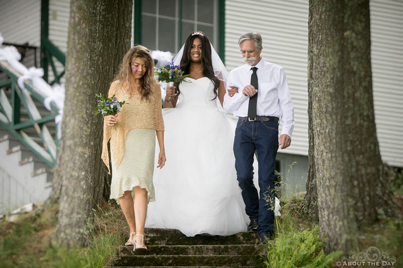Bride is escorted down the stairs by her mother and father