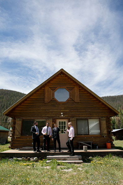 Groom and groomsment hanging out in front of the cabin in Platoro, CO