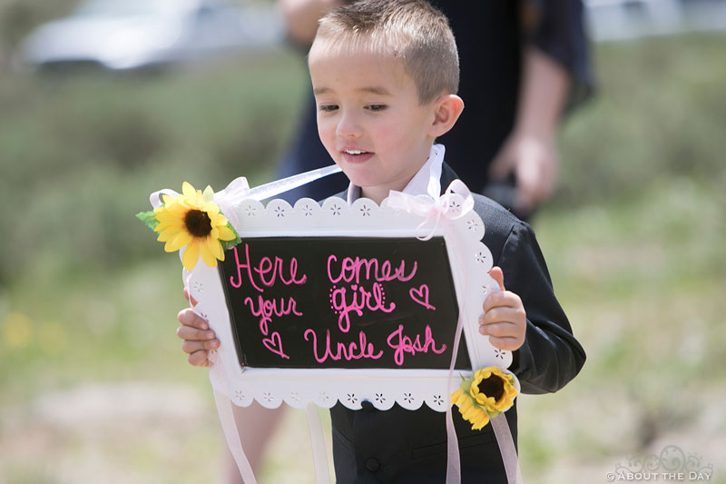 Ring bearer shows sign to introduce the Bride