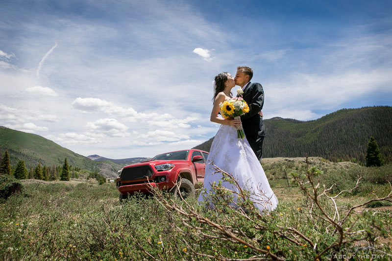 Bride and Groom kiss in front of red Toyota truck