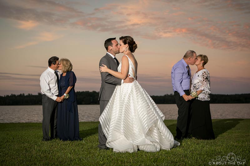 Bride and Groom kiss along with their parents during sunset