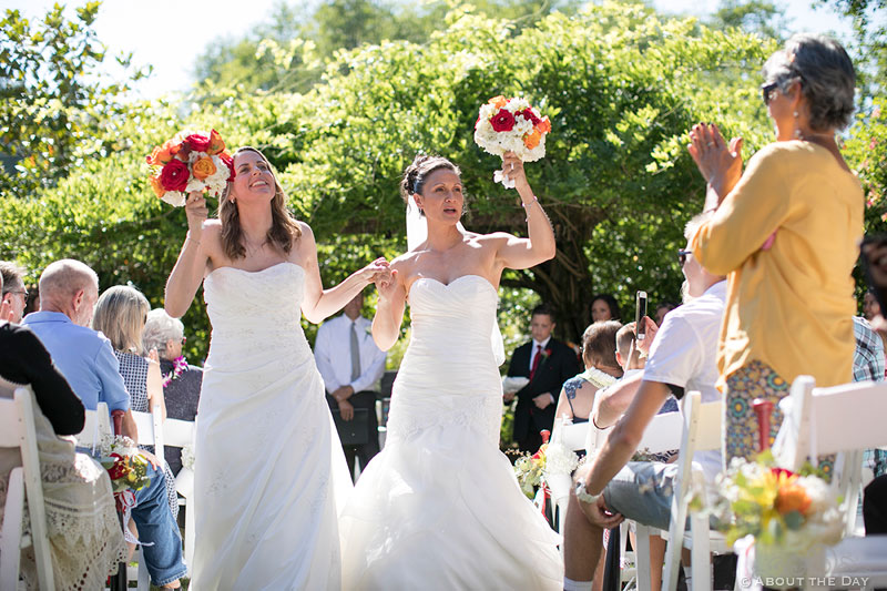 Brides walk down the isle together at Albees Garden in Olympia