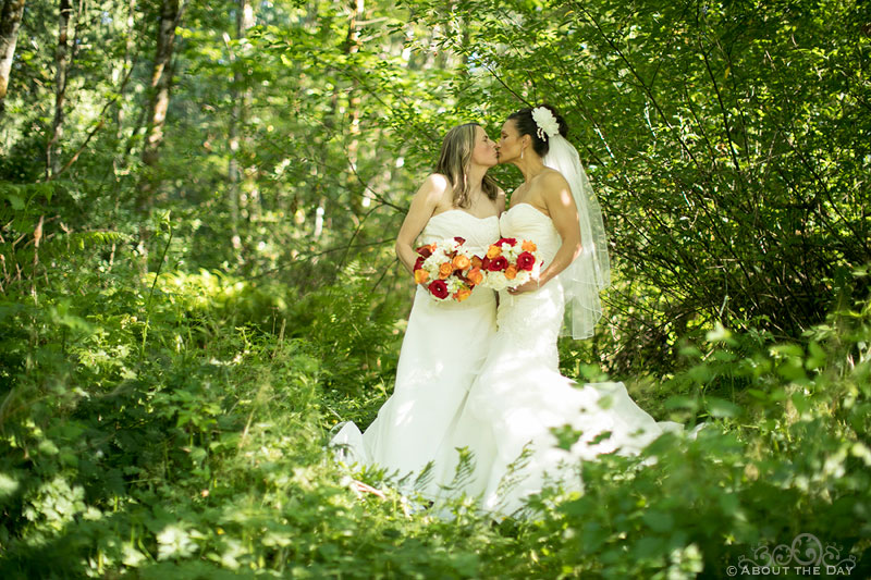 Two beautiful Brides kiss in the woods at Albees Garden in Olympia