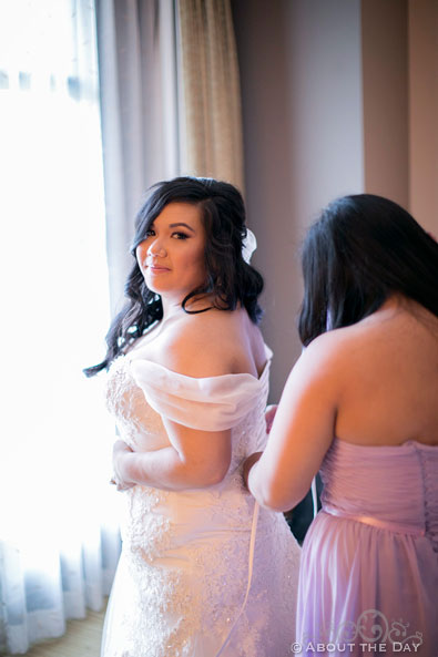 Bride has her dress adjusted by her sister