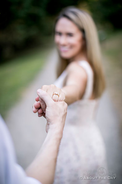 Alex showes her ring in the foreground while leading Andrew