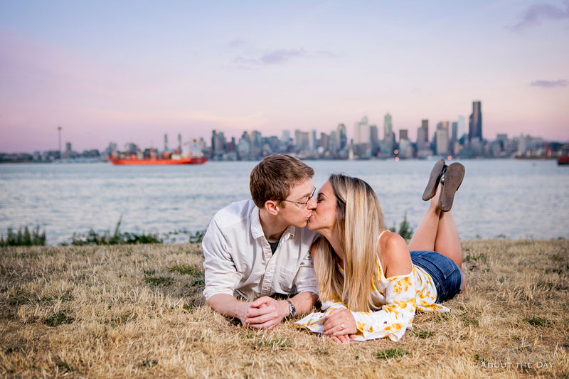 Andrew and Alex kiss beneath the Seattle Skyline during sunset at Alki Beach