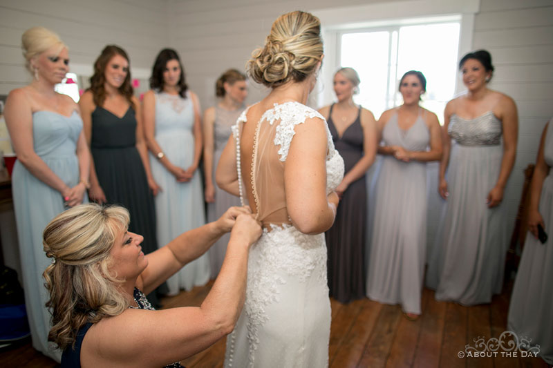 Karleigh's mom adjusts her wedding dress and the bridesmaids watch