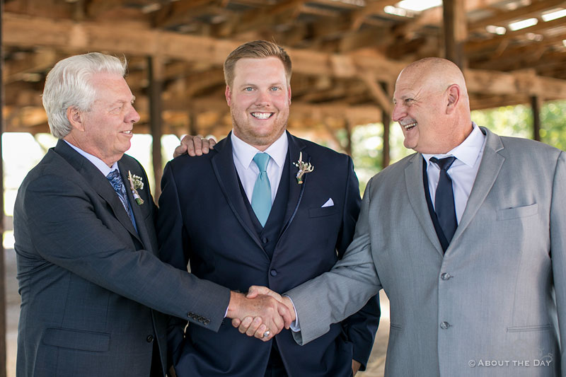 The Grooms dads shake hands in front of him