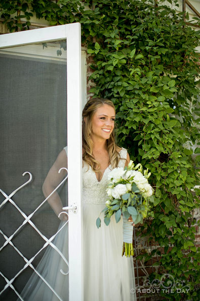 The Bride looks out from the door as the Groom waits