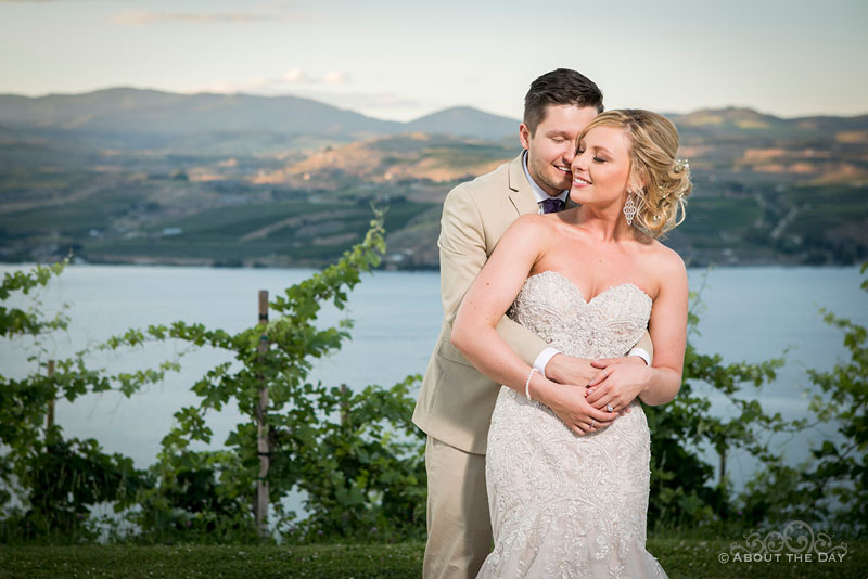 Bride and Groom snuggle with a beautiful view of Lake Chelan during sunset at Karma Vineyards