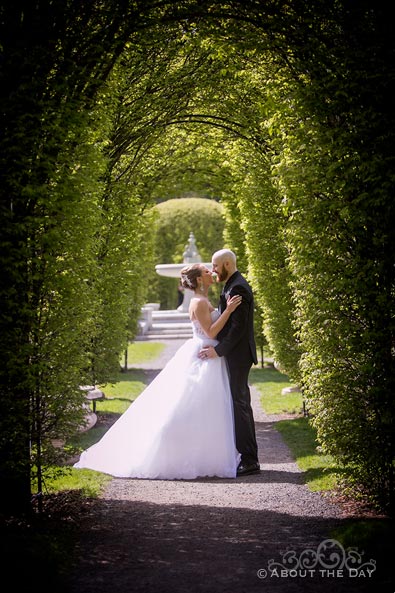 Bride & Groom stand under leafy arches in Cannon Park