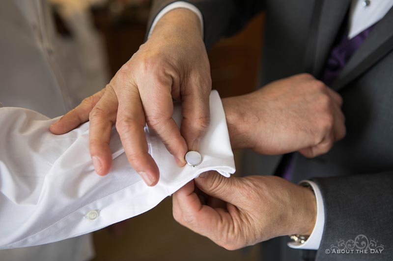 The grooms father helps with his cuff-links