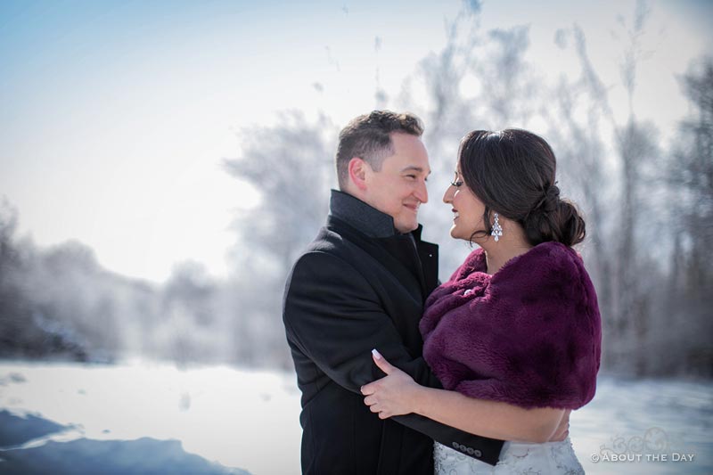 Erik and Faviola snuggle for warmth in their wedding coats in the snow