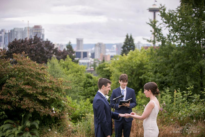 Bride and Groom say their vows in Bhy Kracke Park with a view of the Seattle skyline